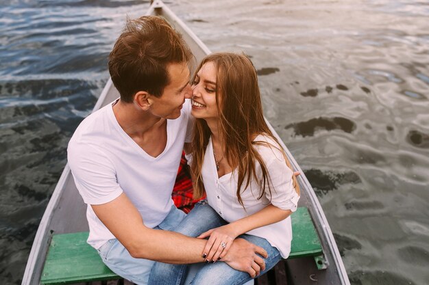 Um cara bonito e uma linda garota descansando em um barco no lago