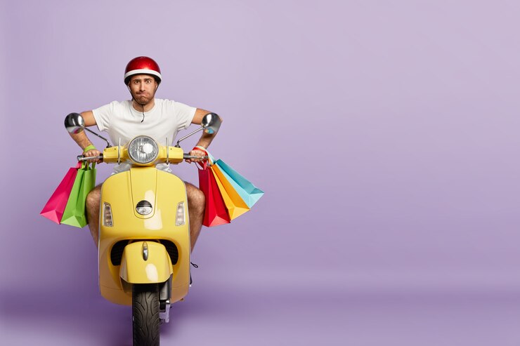 Foto grátis um cara confiante com capacete e sacolas de compras dirigindo uma scooter amarela