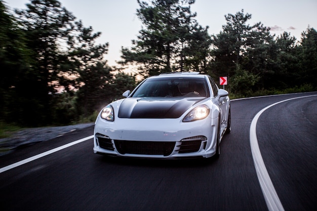 Um carro esporte branco com condução automática preta na estrada.