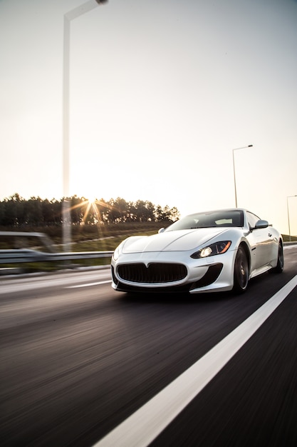 Um carro esporte de cor metálica tira com alta velocidade na estrada.