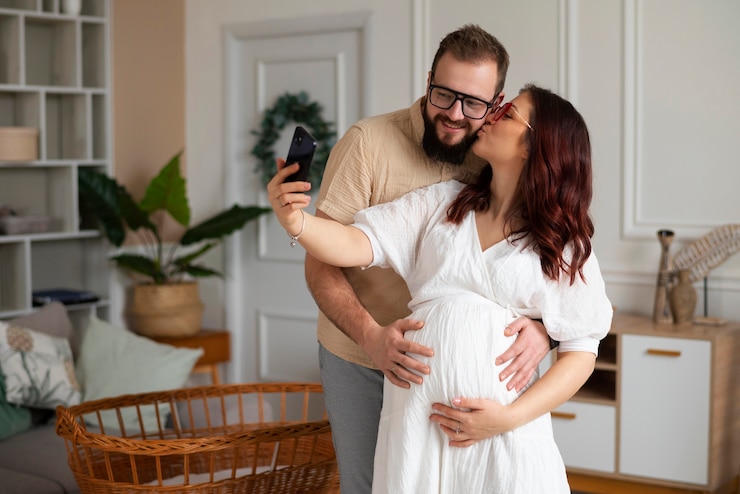 Foto grátis um casal a anunciar a gravidez com um smartphone.