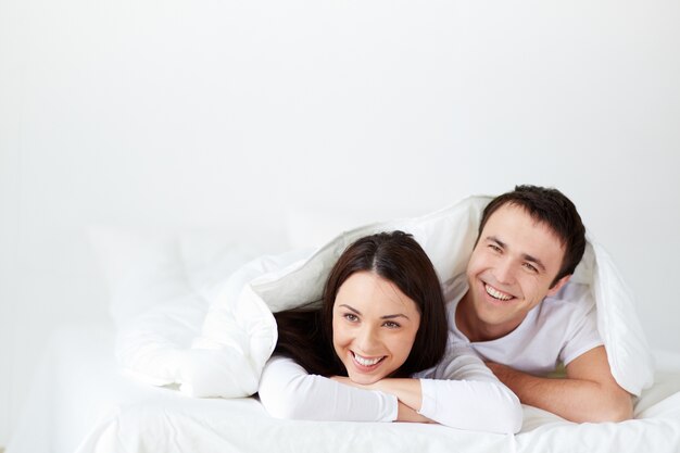 Um casal a rir-se na cama.