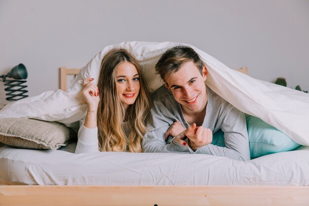 Um casal apaixonado deitado debaixo de um cobertor pesado.