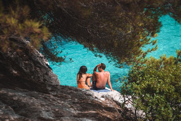 Um casal de homens e mulheres conversando em frente à água turquesa da praia