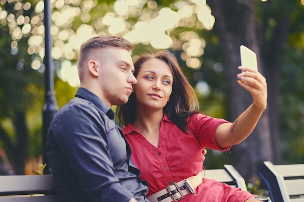 Foto grátis um casal em um encontro em um parque da cidade usando smartphone e mensagens instantâneas.