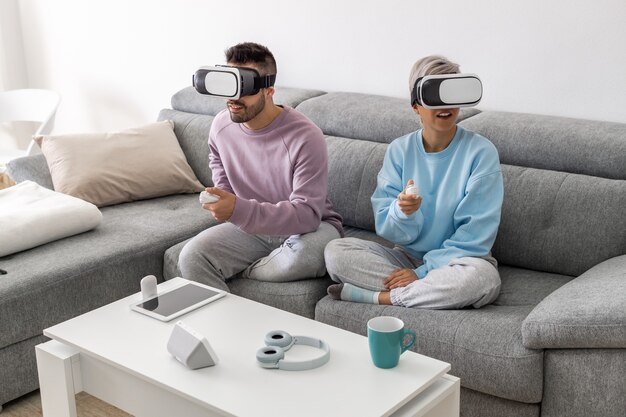 Um casal joga um jogo de realidade virtual usando óculos de realidade virtual enquanto está no sofá da sala de estar.