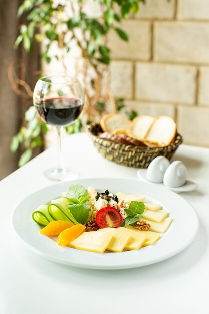 Um close-up frontal vista fatiada frutas frescas maduras, juntamente com vinho tinto na mesa branca