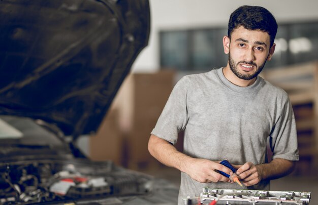 Um colega de bancada reparando os detalhes de um carro e adicionando óleo