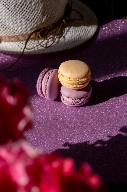 Um conjunto de três macaroons roxos amarelos no fundo de flores de fundo roxo brilhante