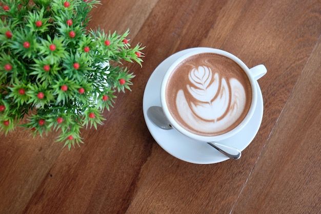 Um copo branco de cacau quente bonito na mesa de madeira