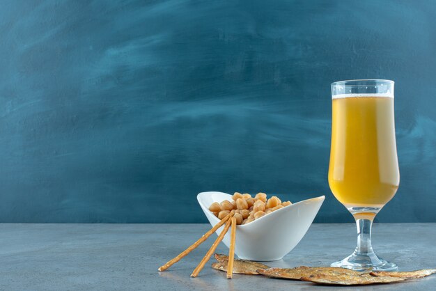 Um copo de cerveja com ervilhas e peixes em fundo cinza. Foto de alta qualidade