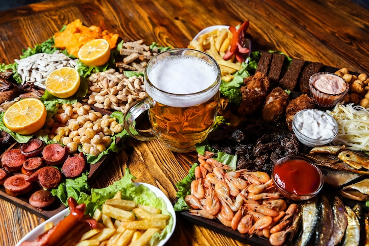 Foto grátis um copo de cerveja com vários lanches para ele na mesa