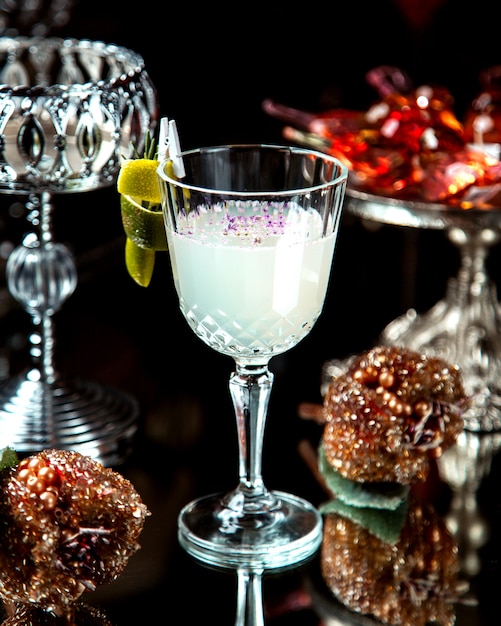 Um copo de cristal com coquetel branco decorado com raspas de limão