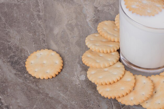 Um copo de leite com biscoitos na mesa de mármore