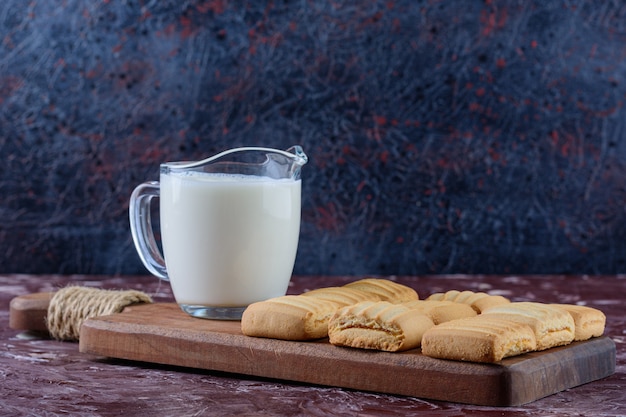 Um copo de leite fresco com biscoitos recém-assados e recheados de frutas