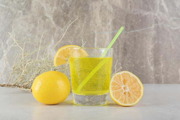 Um copo de limonada com limão e palha na superfície de mármore