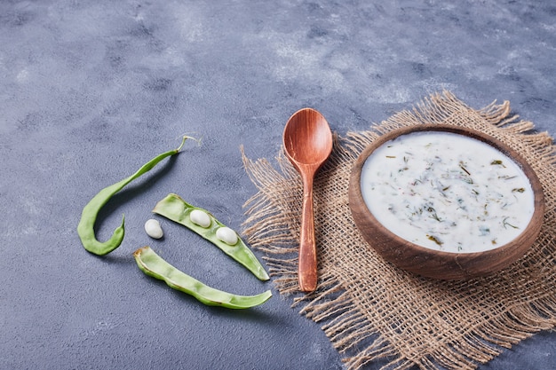 Um copo de madeira de sopa de iogurte com feijão verde.