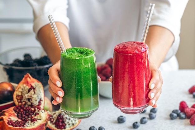 Foto grátis um copo de smoothies vermelhos e verdes em mãos femininas fechadas