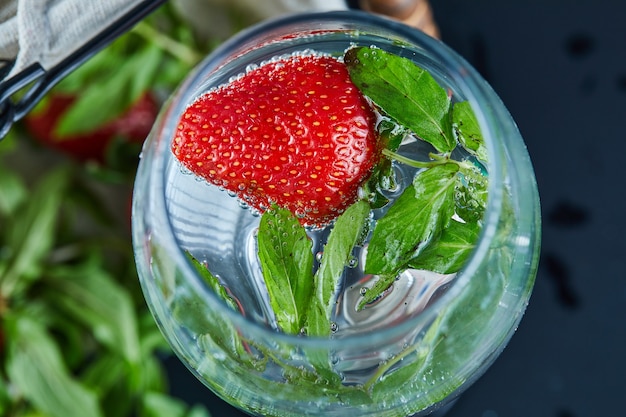 Um copo de suco com frutas inteiras dentro em uma superfície escura