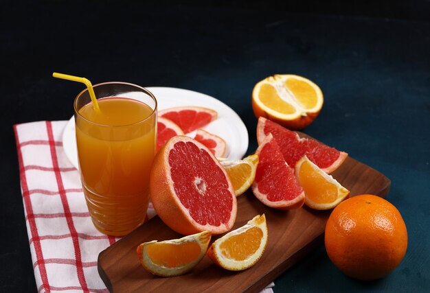 Um copo de suco com laranja e toranjas.