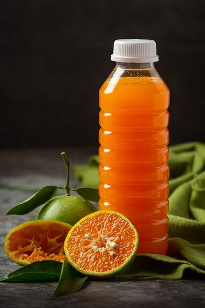 Um copo de suco de laranja e frutas frescas no chão com cubos de gelo.