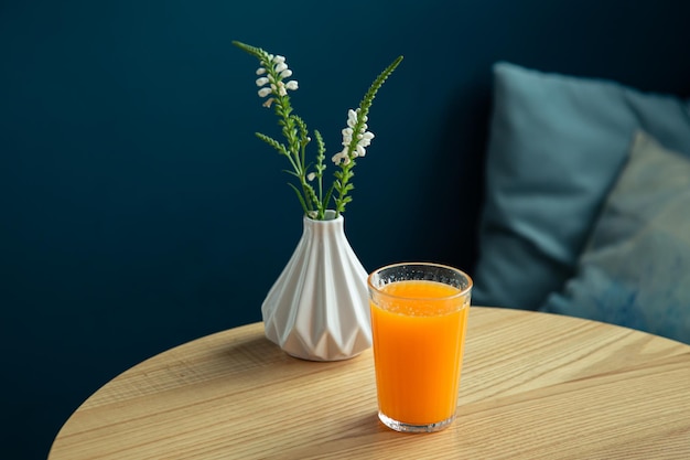 Um copo de suco de laranja em uma mesa em um interior azul