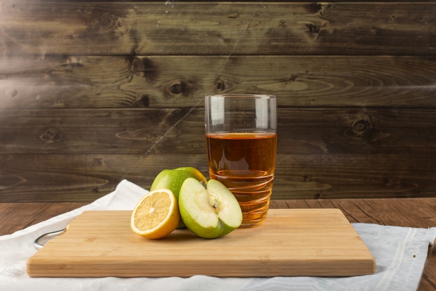 Um copo de suco de maçã com frutas ao redor