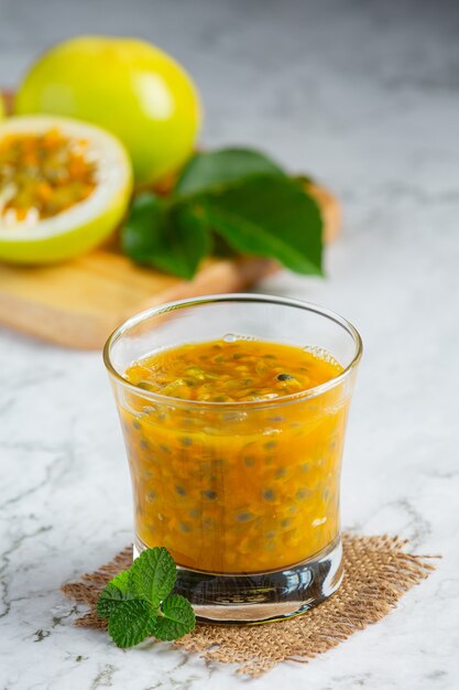 um copo de suco de maracujá colocado no chão de mármore branco