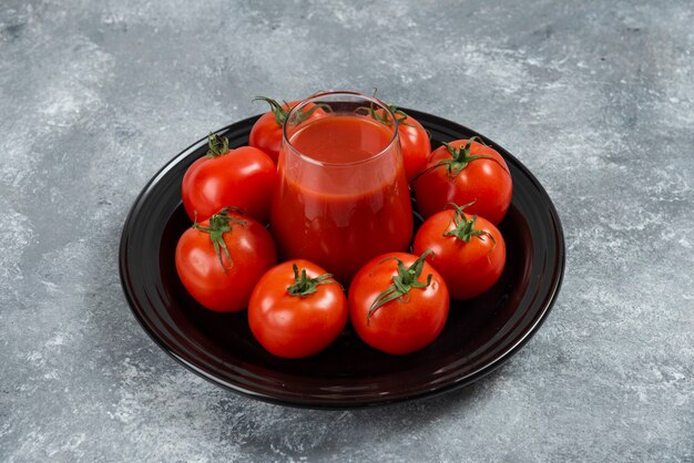 Um copo de suco de tomate em uma placa preta.