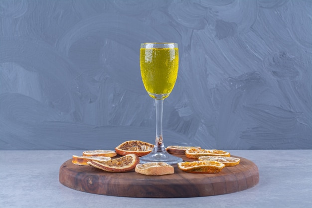 Um copo de suco, fatias de laranja e limão secas a bordo na mesa de mármore.
