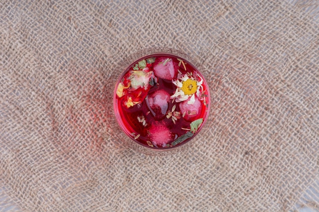 Um copo de suco vermelho na serapilheira com flores. foto de alta qualidade