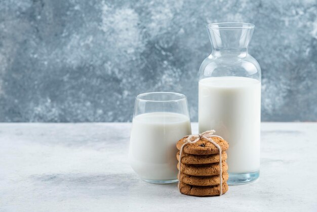 Um copo e um pote de leite com biscoitos deliciosos.