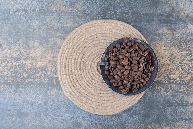 Um copo escuro cheio de grãos de café sobre fundo de mármore. foto de alta qualidade