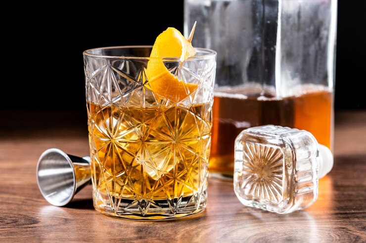 Foto grátis um coquetel à moda antiga adornado com laranja numa mesa de madeira.