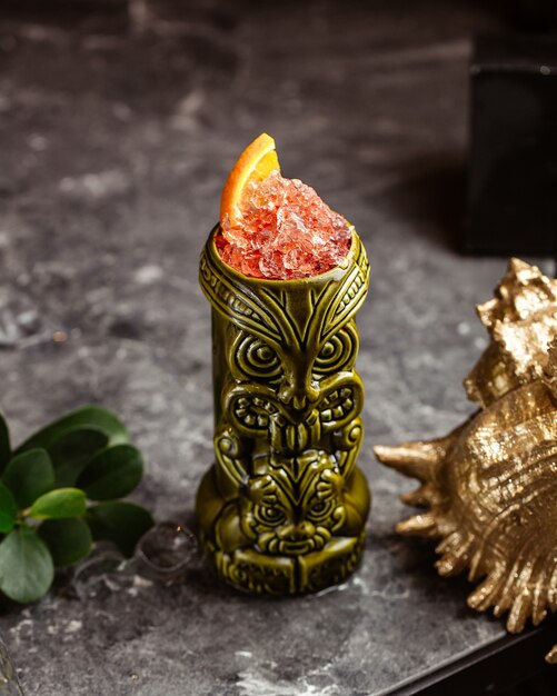 Um coquetel fresco dentro de um copo de souvenir na superfície escura com suco de fruta