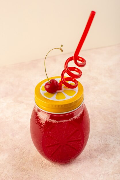 Um coquetel vermelho cereja com canudo dentro de uma pequena lata refrescante em rosa