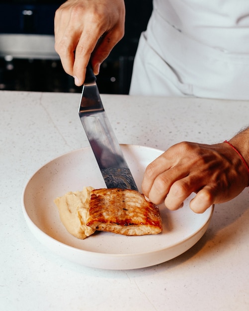 Um cozinheiro de vista superior preparando a refeição em um prato branco e na cozinha