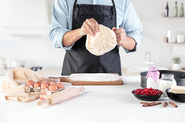 Um cozinheiro em uma cozinha rústica. as mãos masculinas com ingredientes para cozinhar produtos de farinha ou massa, pão, bolos, torta, bolo, pizza