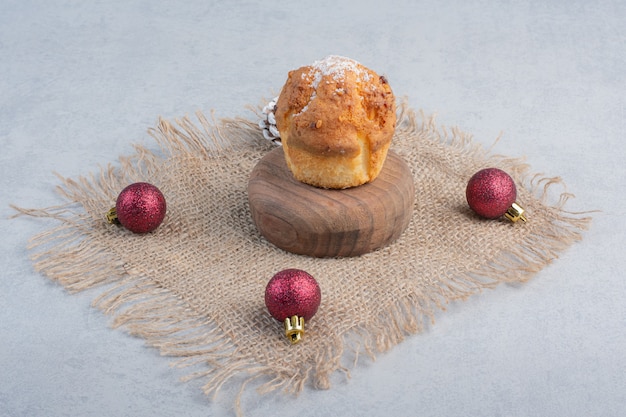 Um cupcake e decorações de natal em um pedaço de pano na superfície de mármore