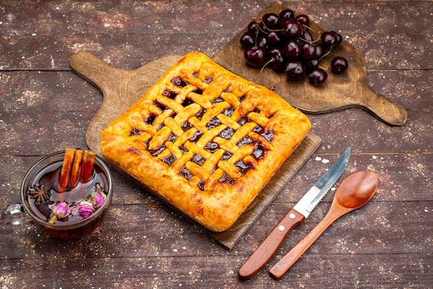 Um delicioso bolo de morango com geleia de cereja de morango e chá na mesa de madeira