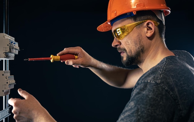 Um eletricista masculino trabalha em um quadro de distribuição com um cabo de conexão elétrico