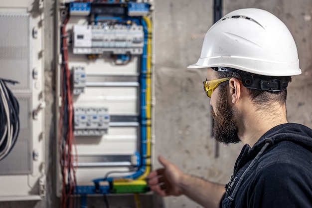 Um eletricista trabalha em uma mesa telefônica com um cabo elétrico de conexão