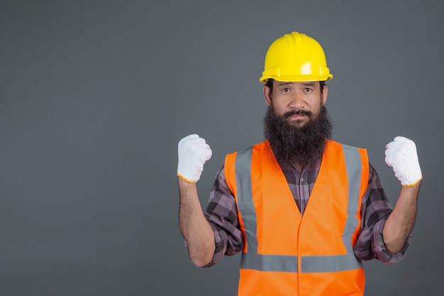 Foto grátis um engenheiro de capacete amarelo, de luvas brancas, mostrou um gesto em cinza.