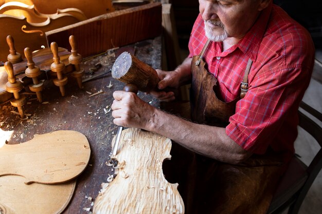 Um experiente carpinteiro sênior de cabelos grisalhos trabalhando em seu projeto em uma oficina de carpintaria