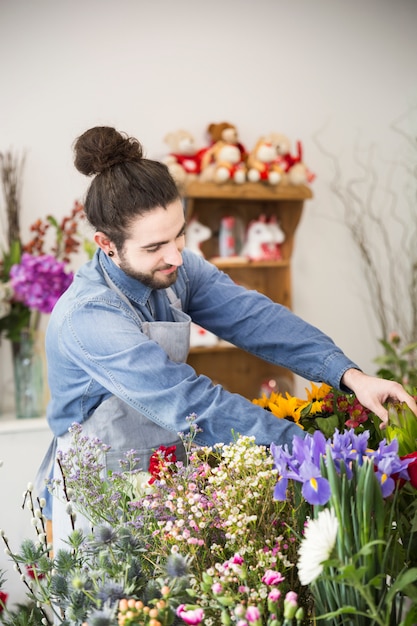 Um florista masculino organizando a flor colorida fresca na loja