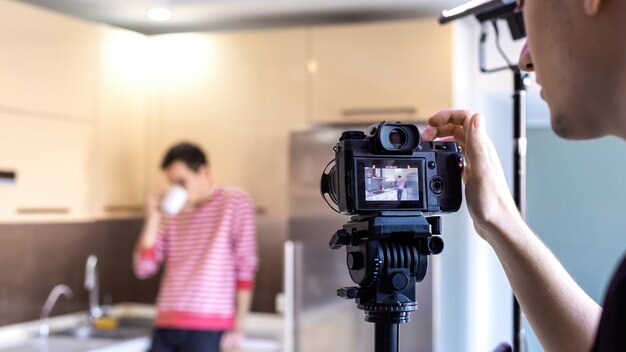 Um fotógrafo fotografando um homem bebendo na cozinha