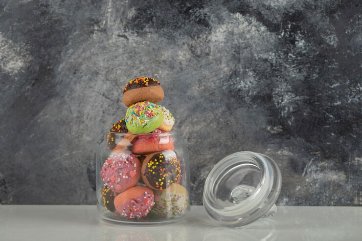 Foto grátis um frasco de vidro cheio de pequenos donuts coloridos.