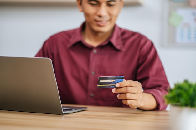 Um funcionário do sexo masculino usa cartão de crédito para pagar mercadorias por meio de um computador.