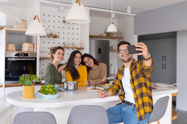 Um grupo de amigos a tirar uma selfie na cozinha.