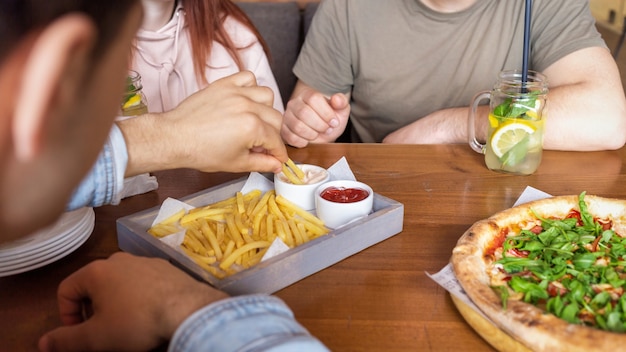 Um grupo de amigos descansando em um bar. Comendo, bebendo, comida na mesa. Amizade